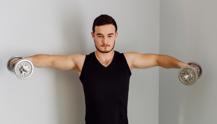 Man performing lateral shoulder raises exercise with dumbbells 