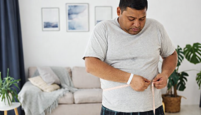 Obese man measuring his waist 