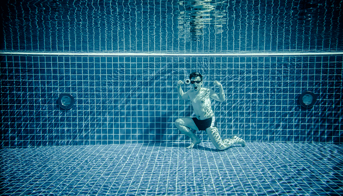 A young boy posing in a swimming pool at lowest level