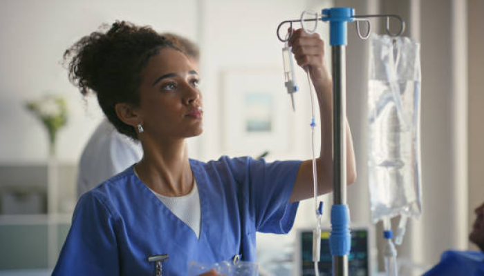 a nurse at the hospital regulating IV fluids for a patient going through refeeding syndrome