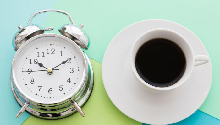A table watch clock and a cup of black coffee